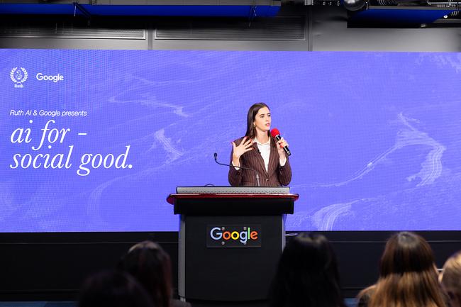 Valerie Chapman speaking behind the Google lectern, with the full AI for Social Good title visible on screen
